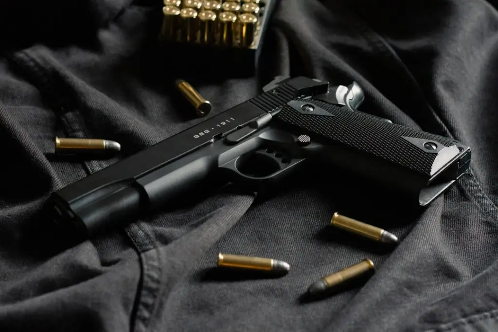 A black handgun on black cloth, with ammunition
