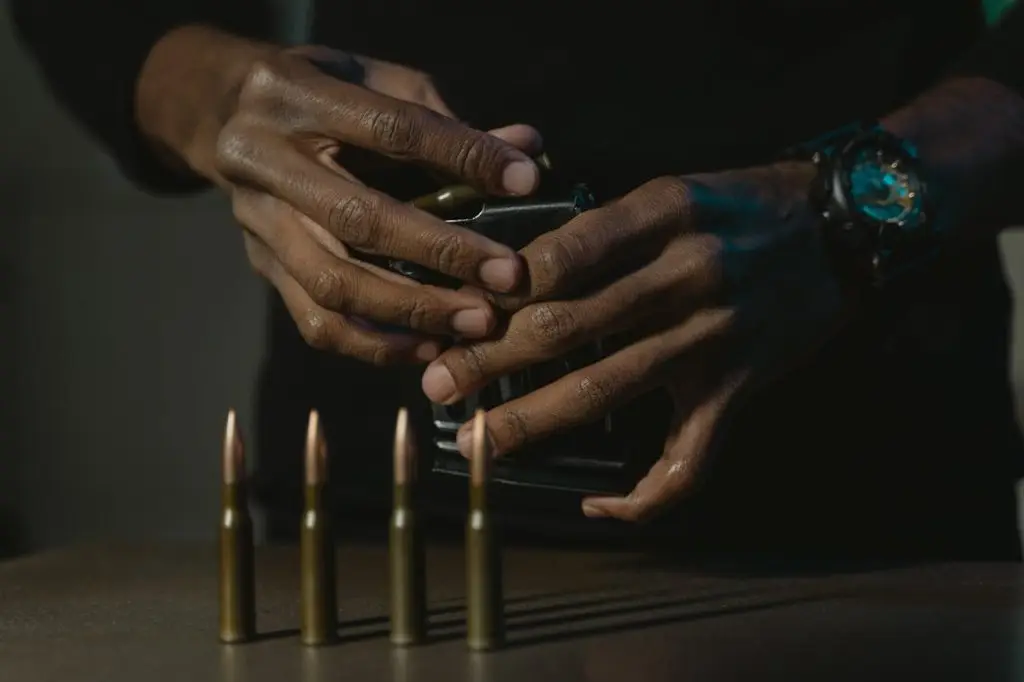 Detailed shot of hands loading bullets into a gun magazine, emphasizing focus and precision.