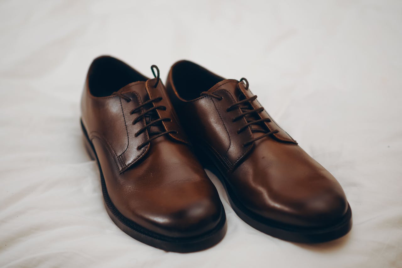 Pair of classic brown leather dress shoes resting on a white surface.