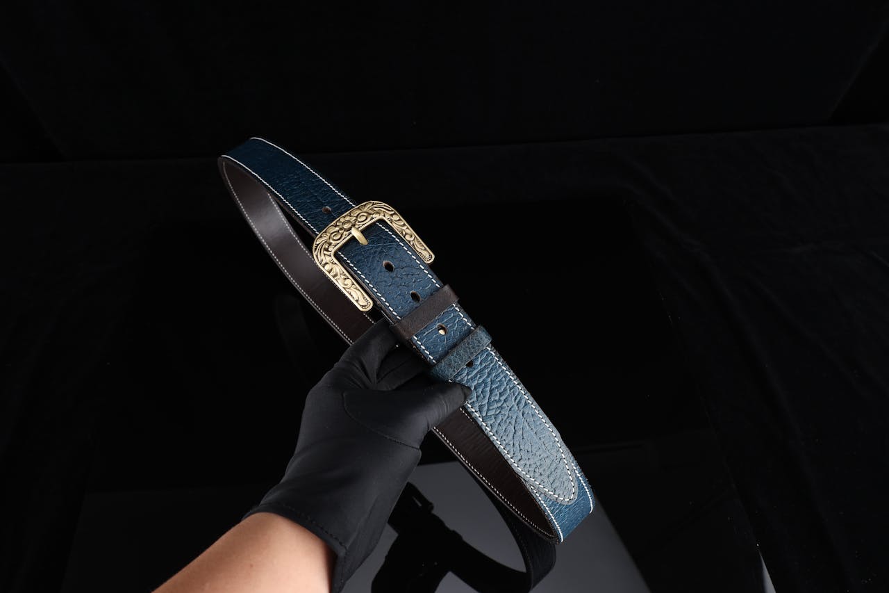 High-quality blue leather belt with intricate gold buckle, a perfect accessory for fashion enthusiasts.